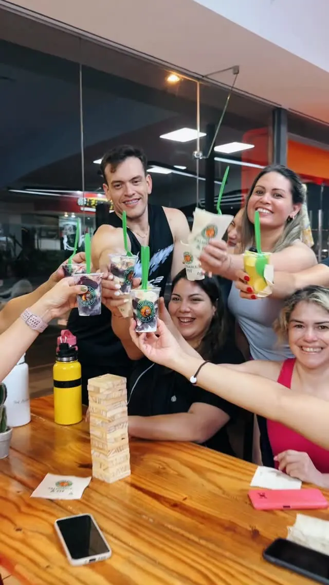Un grupo de amigos brinda levantando sus vasos de camadinha en una mesa del Club Fitness