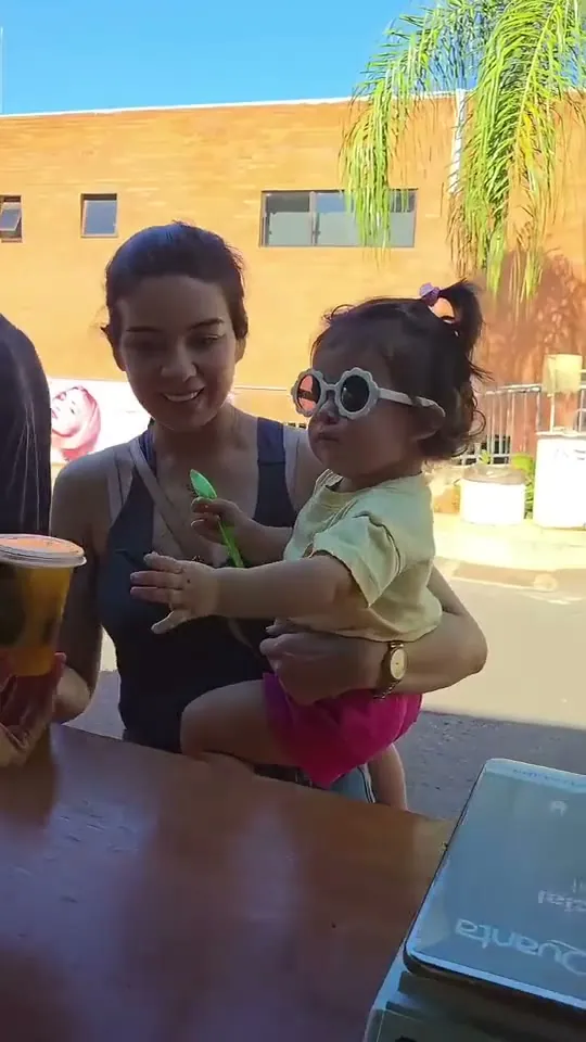 Vasos de Quiero Fruta en la heladera del stand del Intercolegial ASA, y una mamá con su bebé disfrutando un helado