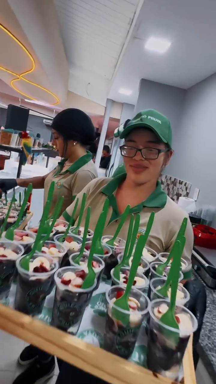 Una integrante del equipo sonríe junto a una bandeja con camadinhas de açaí