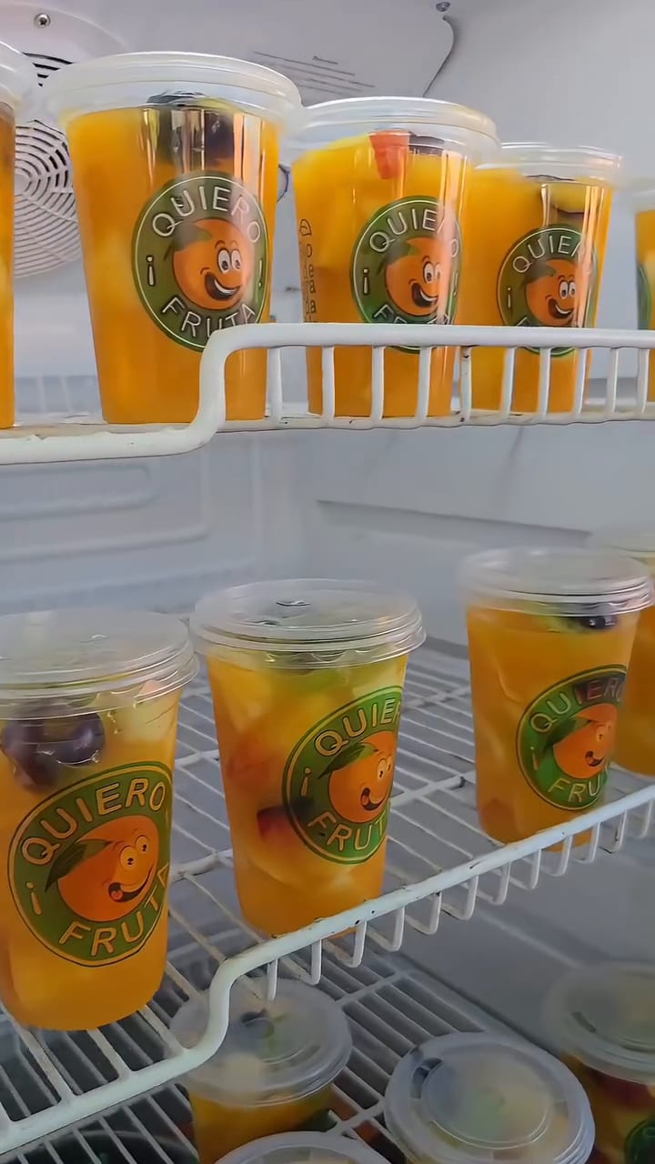 Vasos de jugo natural con la marca Quiero Fruta, fríos, en una heladera
