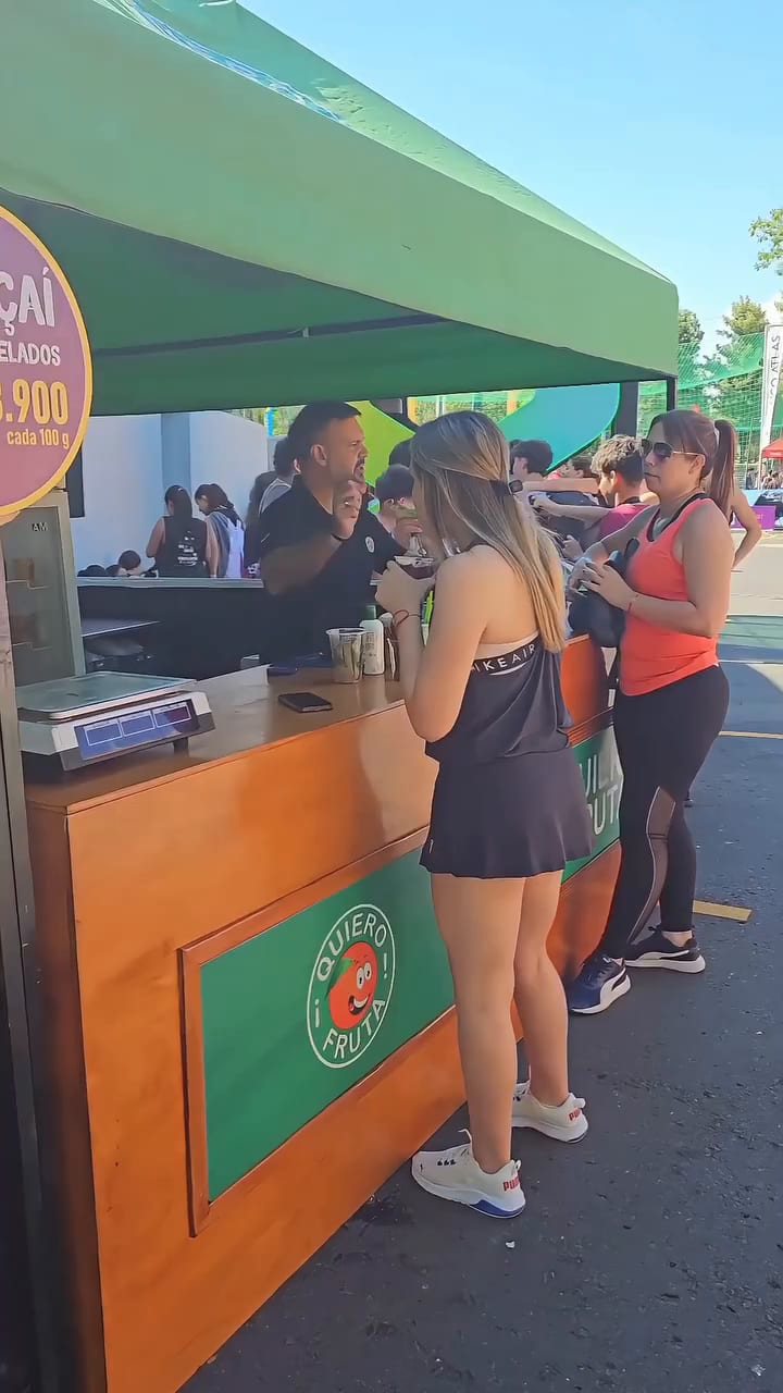 El stand Self Service QF con toldo verde y mostrador naranja, en un evento